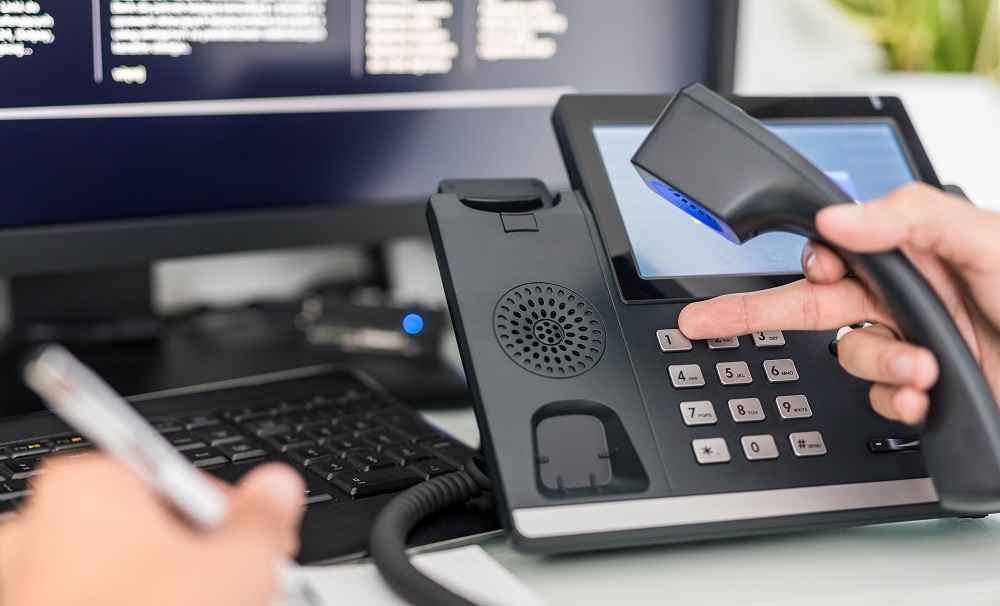 Man using a VoIP compatible desk phone for VoIP calls